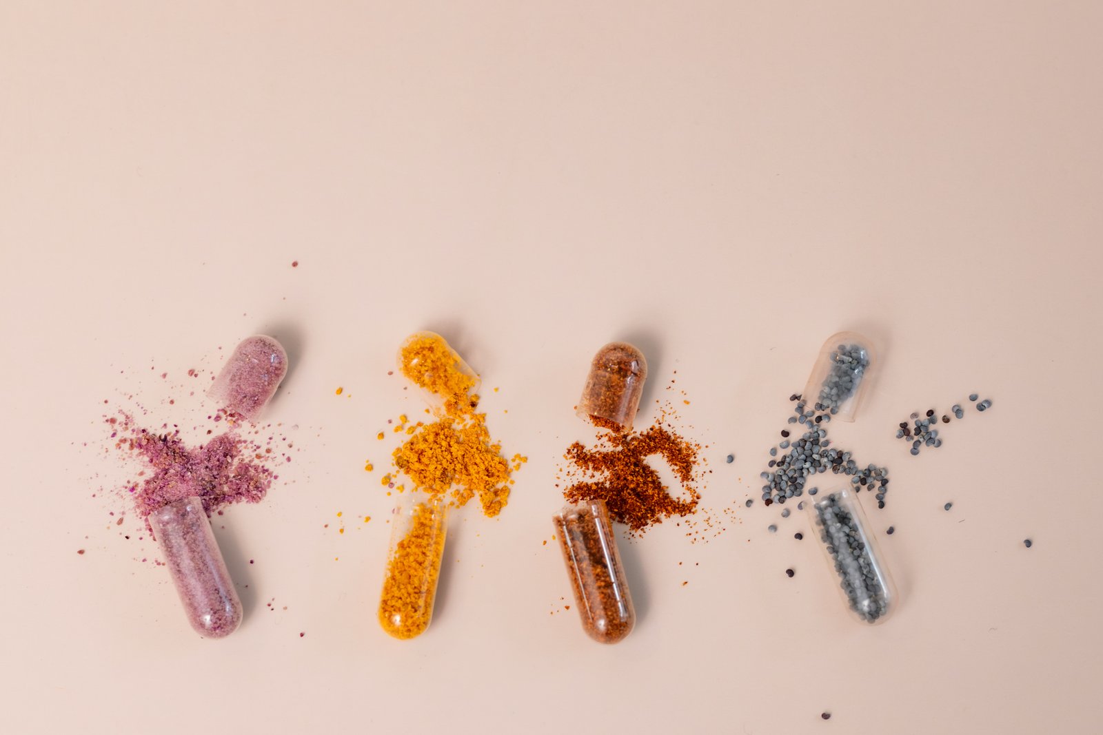 Compresse e capsule di vitamine sparse accanto a un flacone aperto su un piano chiaro